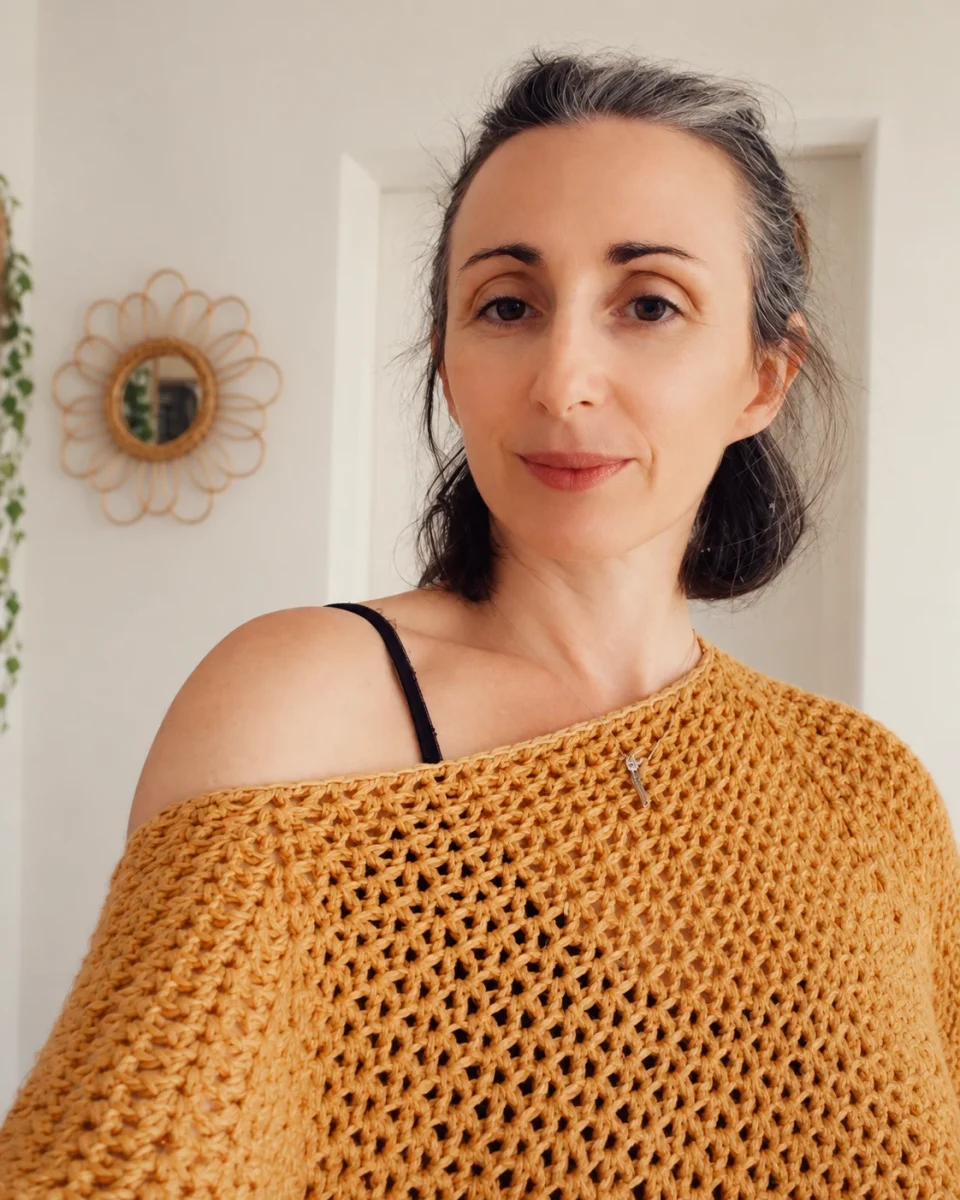 Créatrice d'AEL Créations portant un poncho crocheté couleur moutarde